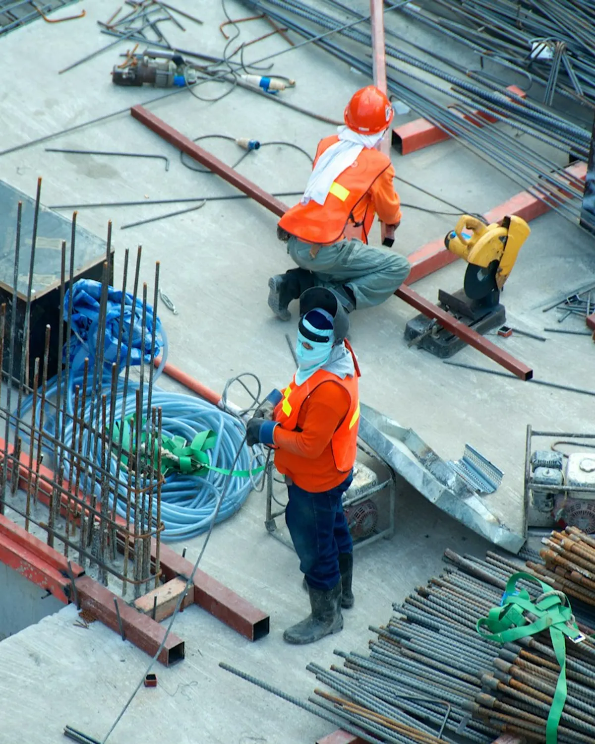 Construction crew cutting structural steel on a concrete deck during active build work