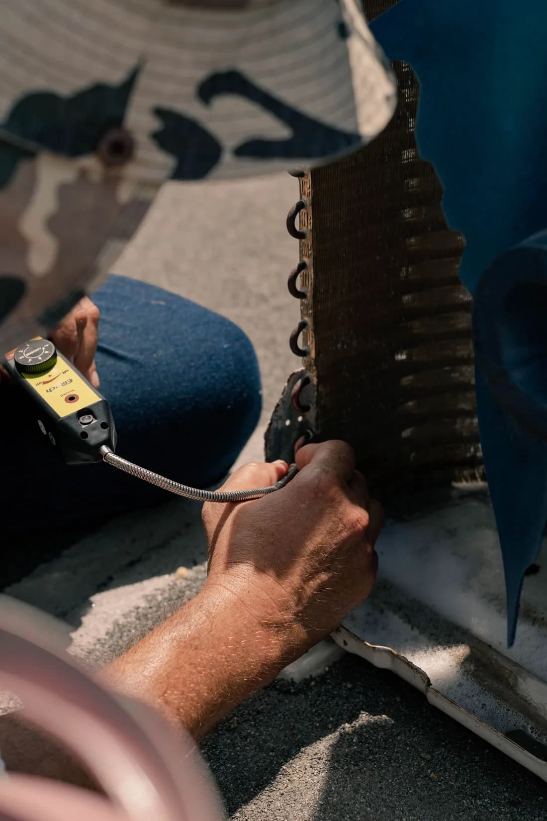Technician testing outdoor AC condenser coils with a handheld service tool