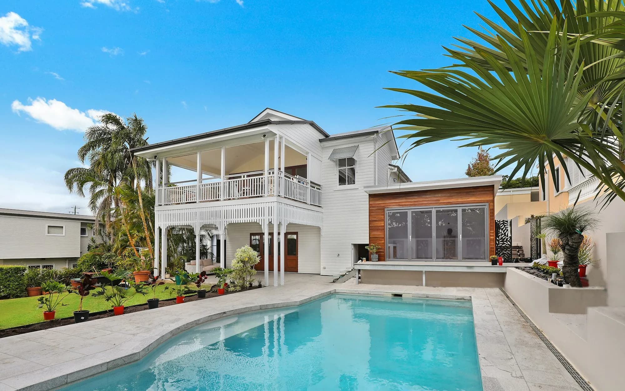 Modern white Florida custom home with pool, wood accents, and palm trees