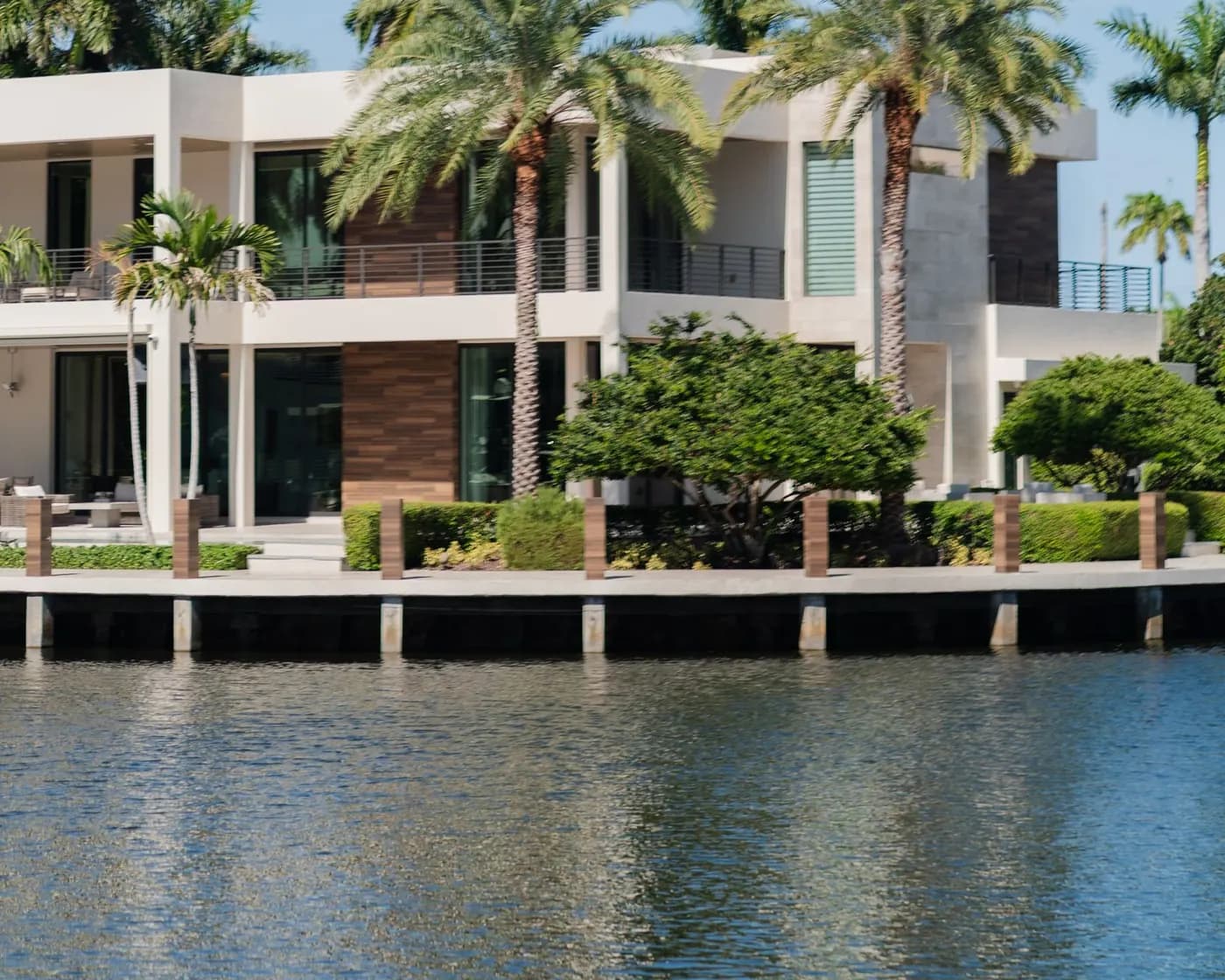 Modern Miami waterfront villa with palm trees and wooden dock edge