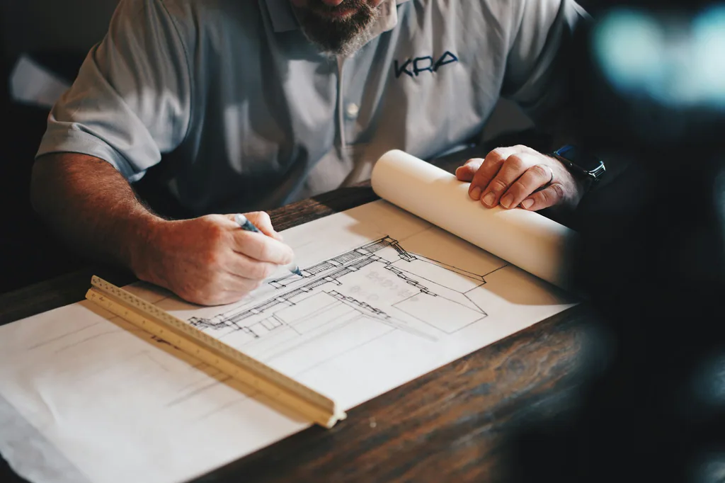 Contractor reviewing architectural blueprints and project measurements during a residential planning session.
