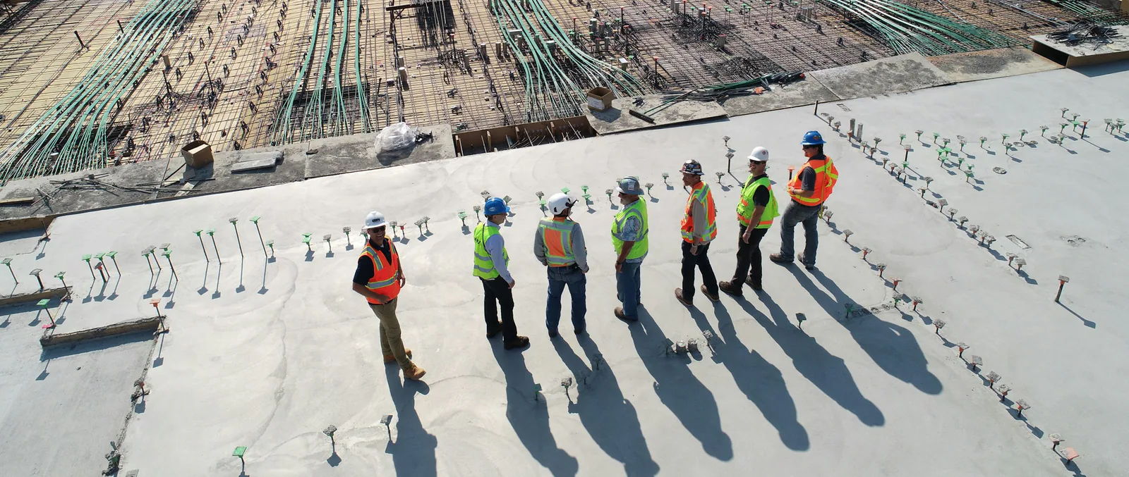 Professional construction crew working on a modern residential building site with safety equipment and branded presence.