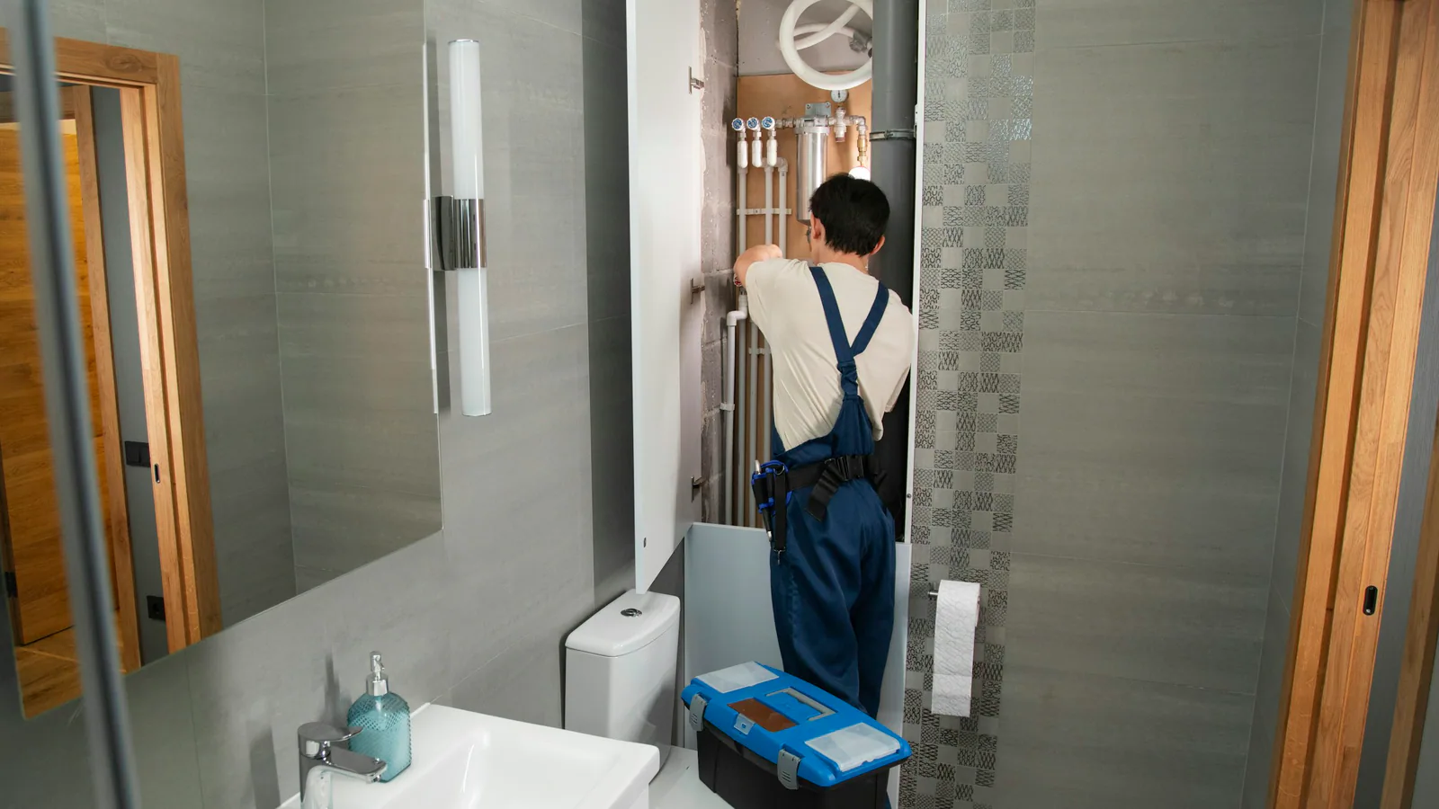 Licensed plumber inspecting pipe connections during a residential service call.